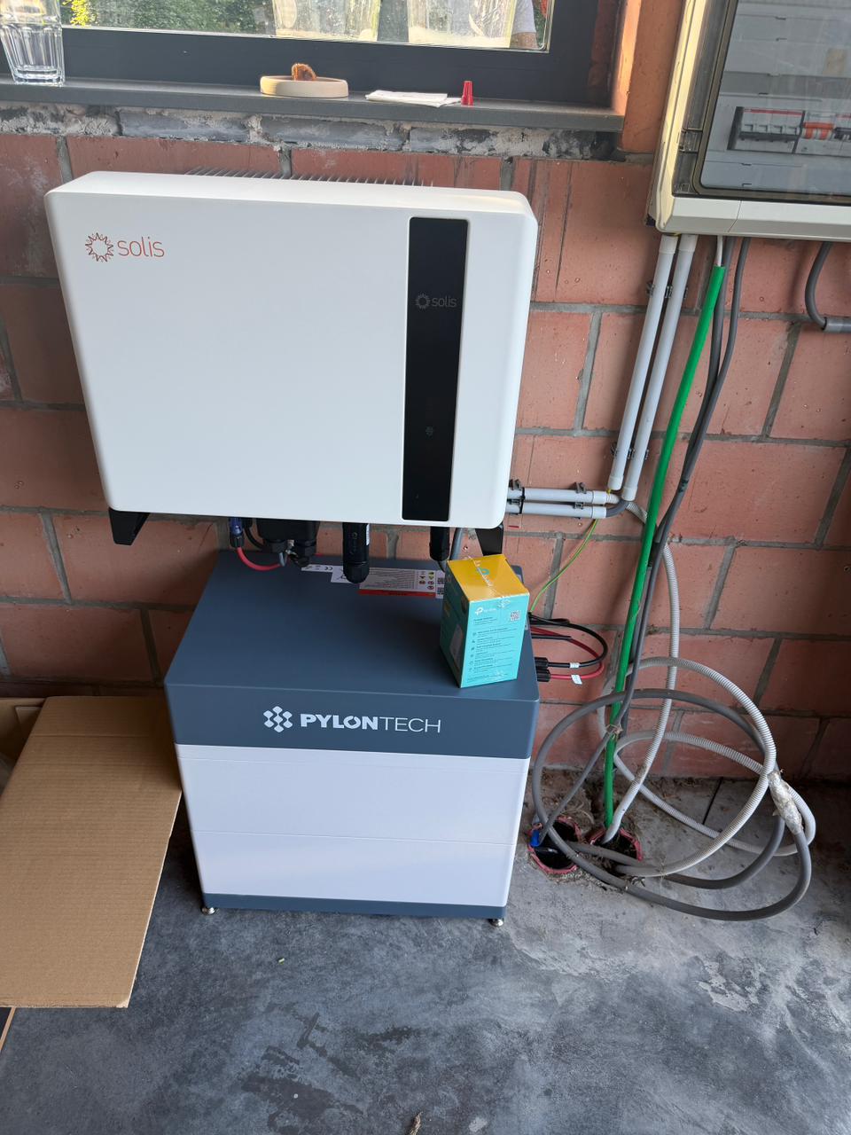 Solis omvormer op een gestapelde Pylontech batterijtoren tegen een bakstenen muur in een garage